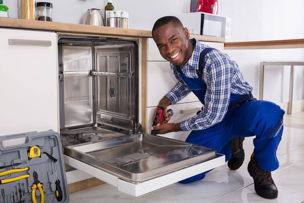 Repairman Installing Dishwasher In Kitchen
